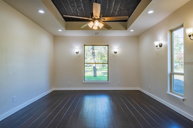 spare room with ceiling fan, dark hardwood / wood-style flooring, and a tray ceiling