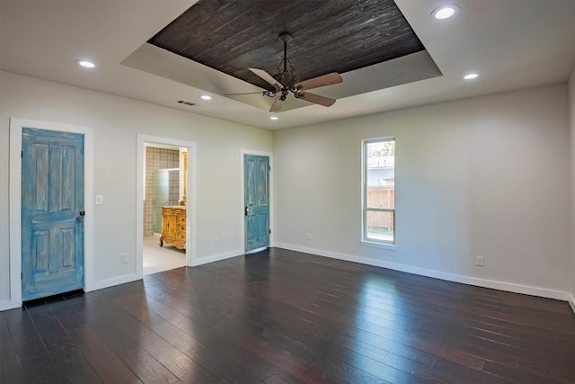 spare room with dark hardwood / wood-style floors, ceiling fan, and a tray ceiling