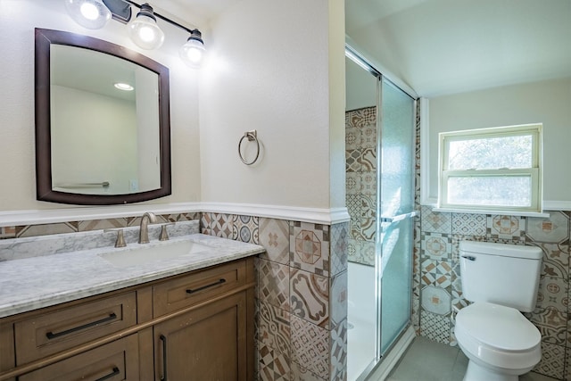 bathroom featuring tile patterned floors, walk in shower, vanity, tile walls, and toilet