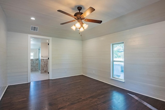 unfurnished room featuring ceiling fan, wood walls, and dark hardwood / wood-style floors