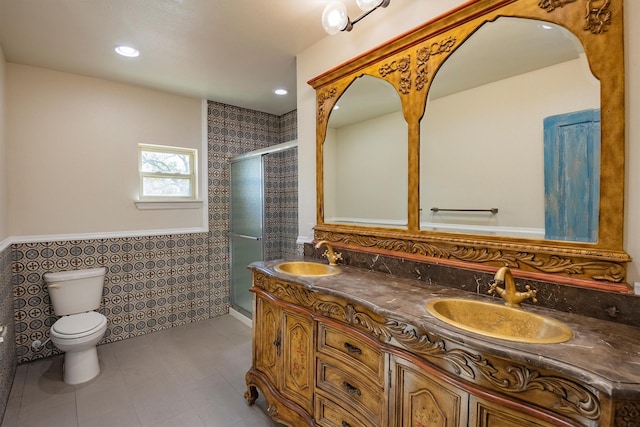 bathroom featuring tile patterned floors, a tile shower, vanity, tile walls, and toilet