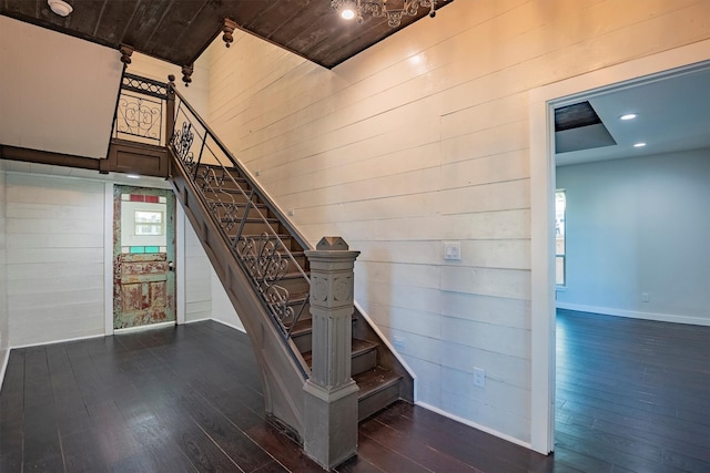 stairs with wood-type flooring, plenty of natural light, and wood walls