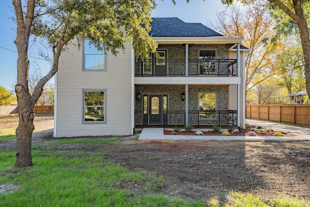 rear view of property featuring a porch and a balcony