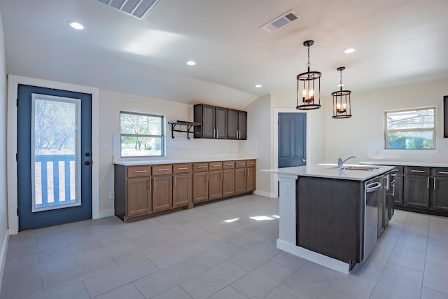 kitchen with pendant lighting, an inviting chandelier, a wealth of natural light, and an island with sink