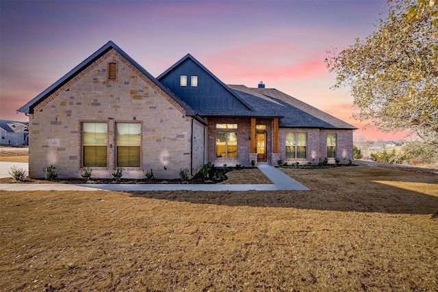 view of front facade with board and batten siding, a front yard, and roof with shingles