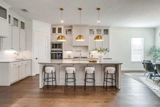 kitchen featuring built in microwave, a kitchen island with sink, a breakfast bar, and oven