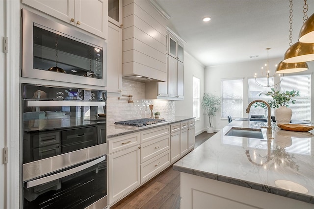 kitchen with sink, light stone counters, dark hardwood / wood-style flooring, pendant lighting, and appliances with stainless steel finishes