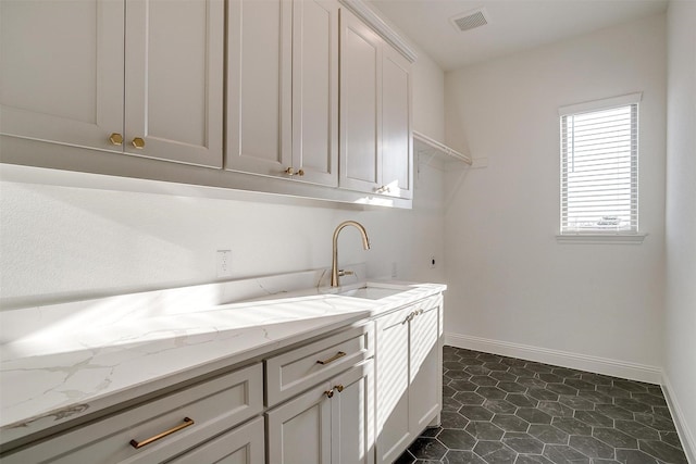 laundry room featuring cabinets, dark tile patterned floors, and sink