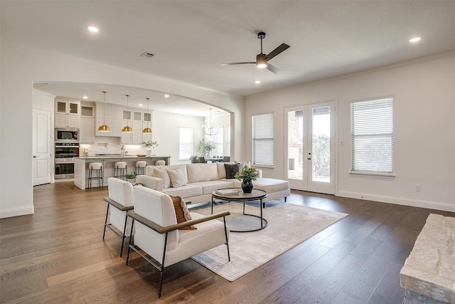 living room with dark hardwood / wood-style floors, crown molding, ceiling fan with notable chandelier, and french doors