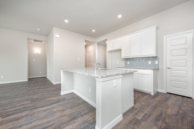 kitchen with white cabinets, dark hardwood / wood-style floors, decorative backsplash, and a kitchen island with sink