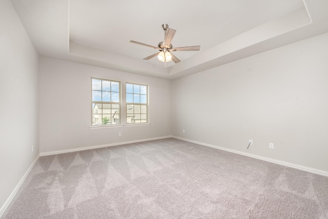 unfurnished room with light carpet, a tray ceiling, and ceiling fan