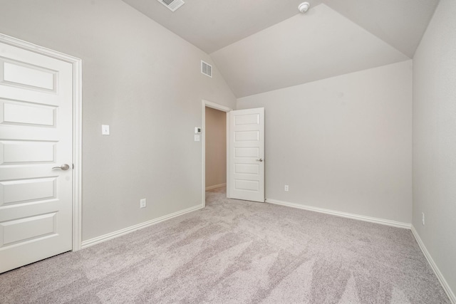 carpeted spare room with vaulted ceiling