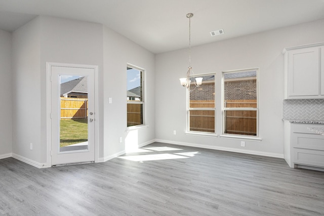 unfurnished dining area with light hardwood / wood-style floors and a notable chandelier