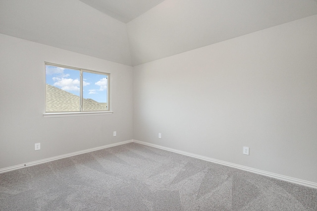 carpeted empty room featuring vaulted ceiling