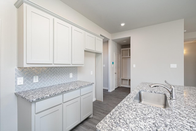 kitchen with light stone countertops, white cabinets, dark hardwood / wood-style floors, and sink