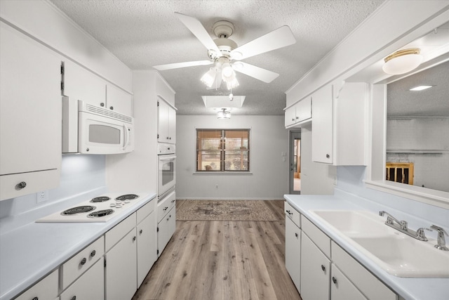 kitchen featuring sink, white cabinetry, a textured ceiling, light hardwood / wood-style flooring, and white appliances