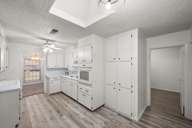 kitchen featuring white cabinetry, white appliances, ceiling fan with notable chandelier, and light wood-type flooring