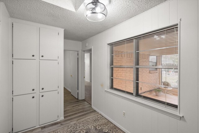 unfurnished bedroom featuring a textured ceiling, light hardwood / wood-style floors, and a closet