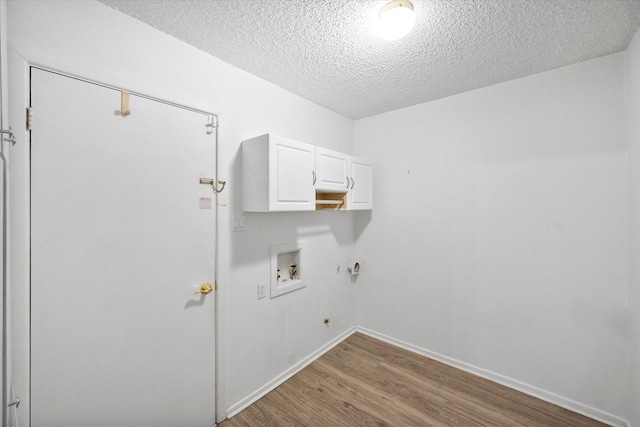 clothes washing area with gas dryer hookup, hookup for a washing machine, cabinets, light hardwood / wood-style floors, and a textured ceiling