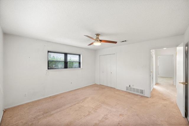 carpeted spare room with ceiling fan and a textured ceiling