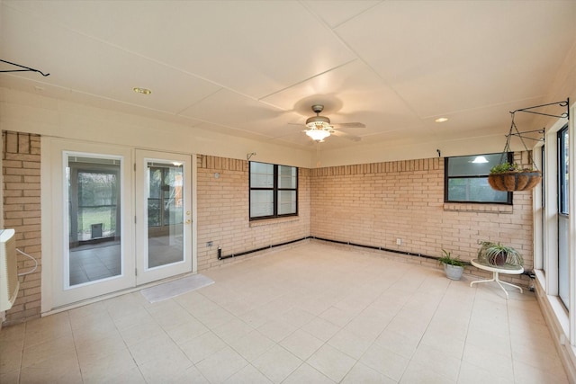 unfurnished sunroom featuring ceiling fan