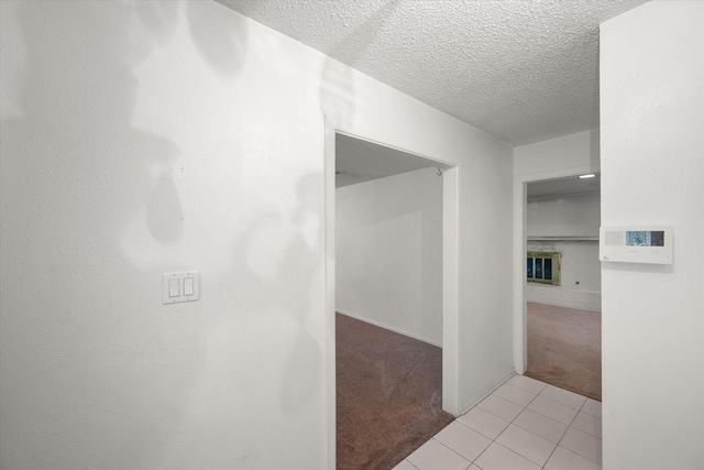 hall featuring light carpet and a textured ceiling