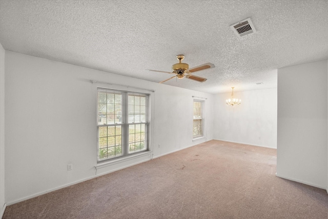 carpeted empty room featuring ceiling fan with notable chandelier and a textured ceiling