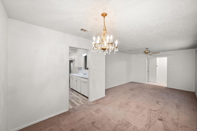 carpeted spare room featuring ceiling fan with notable chandelier, sink, and a textured ceiling