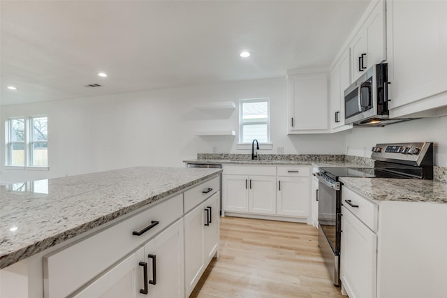 kitchen with white cabinetry, appliances with stainless steel finishes, light stone countertops, and sink