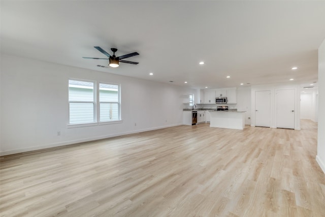 unfurnished living room featuring ceiling fan, sink, and light hardwood / wood-style floors