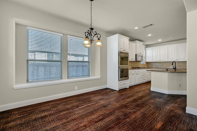 kitchen with dark wood-type flooring, white cabinetry, pendant lighting, stainless steel appliances, and decorative backsplash