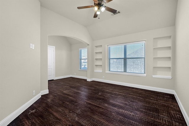 unfurnished room with lofted ceiling, built in features, dark hardwood / wood-style floors, and ceiling fan