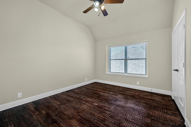 empty room featuring ceiling fan, dark hardwood / wood-style floors, and vaulted ceiling