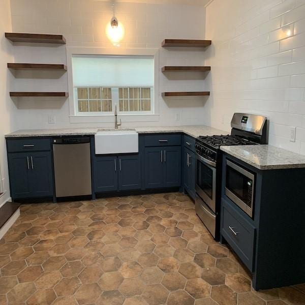 kitchen featuring stainless steel appliances, light stone countertops, and sink