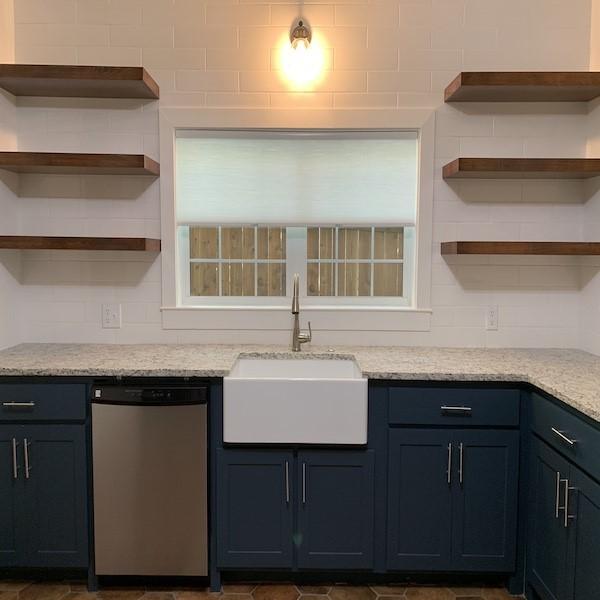 kitchen featuring light stone counters, dishwasher, and sink