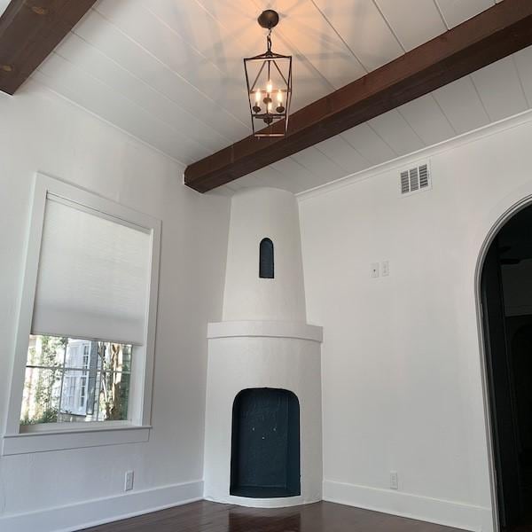 unfurnished living room with a notable chandelier and beam ceiling