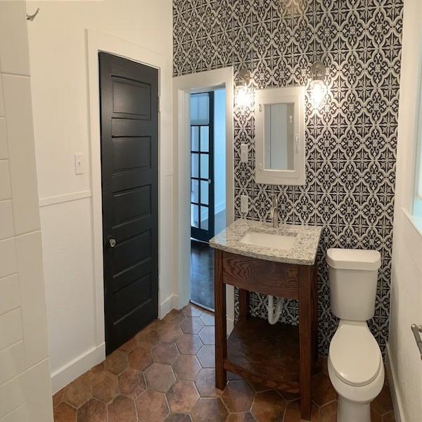 bathroom with toilet, tile walls, and sink