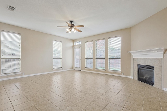 unfurnished living room with ceiling fan, light tile patterned floors, and a tile fireplace