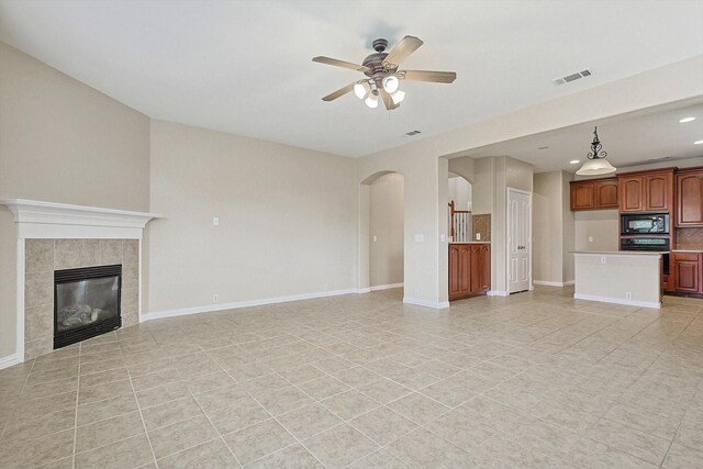 unfurnished living room featuring light tile patterned floors, ceiling fan, and a tiled fireplace