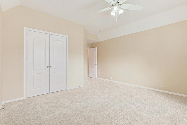 unfurnished bedroom featuring ceiling fan, lofted ceiling, light carpet, and a closet