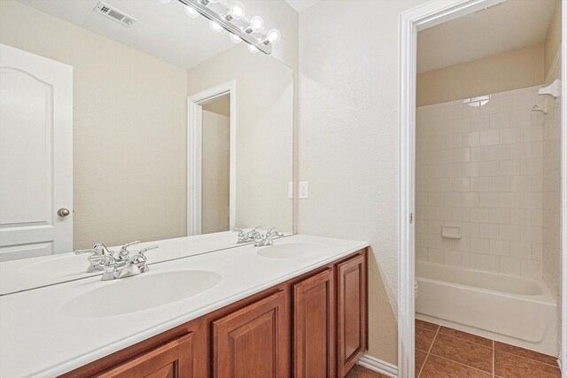 bathroom with tile patterned floors, vanity, and tiled shower / bath combo