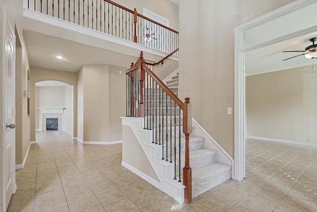 stairway with tile patterned flooring, ceiling fan, and a tile fireplace