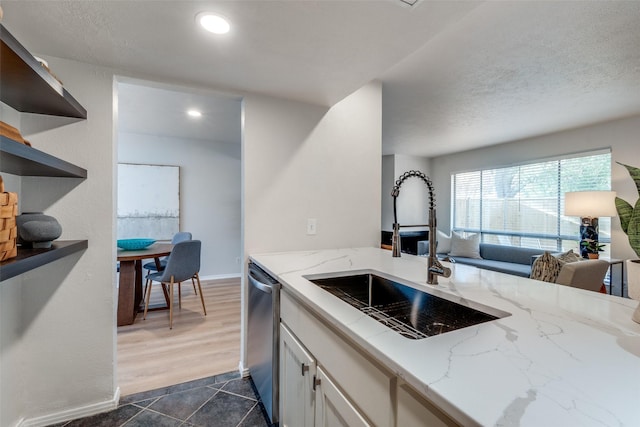 kitchen with light stone countertops, sink, stainless steel dishwasher, dark hardwood / wood-style floors, and white cabinets