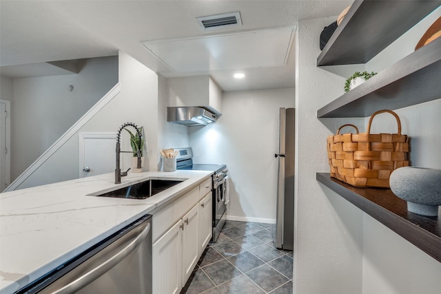 kitchen with white cabinetry, sink, stainless steel appliances, light stone counters, and dark tile patterned flooring