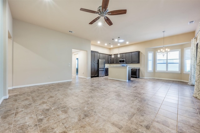 kitchen with dark brown cabinets, a kitchen island, pendant lighting, stainless steel appliances, and ceiling fan with notable chandelier