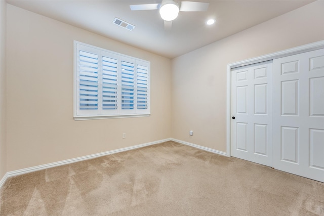 unfurnished bedroom with ceiling fan, light colored carpet, and a closet