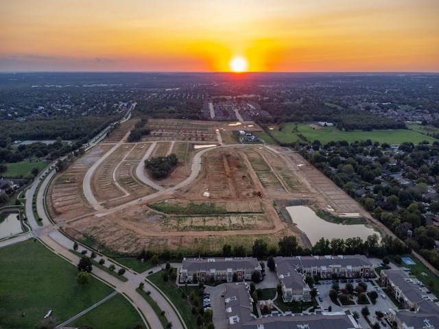 aerial view at dusk featuring a water view