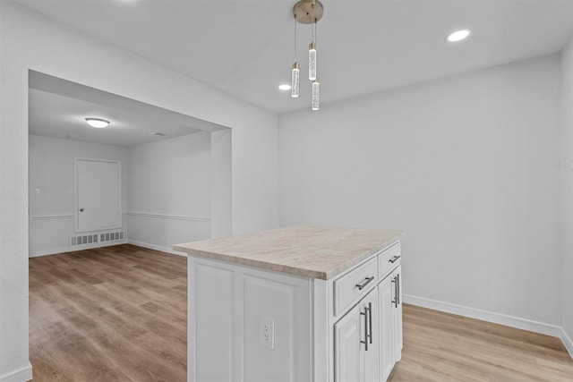 kitchen featuring light wood-type flooring, decorative light fixtures, white cabinetry, and a kitchen island