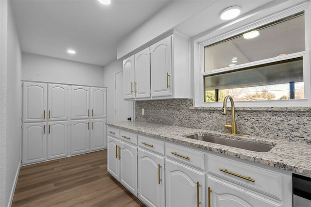 kitchen with white cabinets, hardwood / wood-style floors, backsplash, and sink