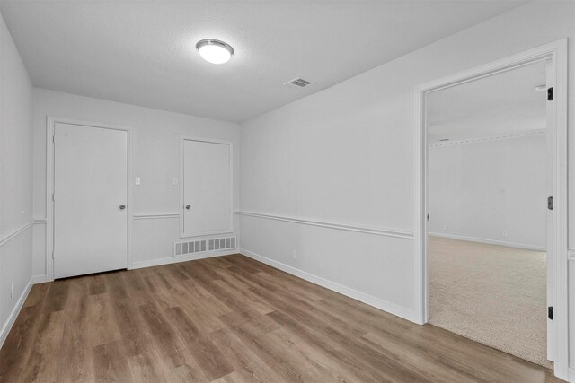 spare room featuring light hardwood / wood-style floors and a textured ceiling